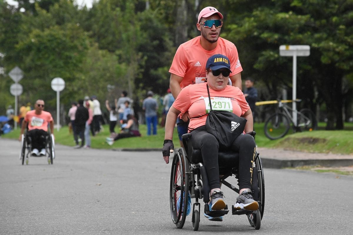 Mujer discapacitada en silla de ruedas corriendo la media maratón de bogotá 2023.